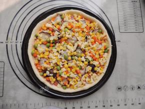 将香菇和什锦杂蔬粒铺在饼底上，铺完蔬菜，再撒一层芝士。