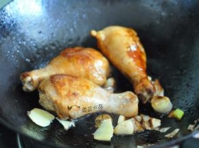 放入鸡腿煎至两面上色，放入葱、姜、蒜。