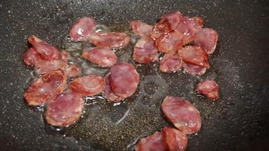 锅里加适量的食用油，下腊肠翻炒出油脂。