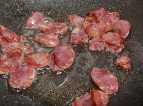 锅里加适量的食用油，下腊肠翻炒出油脂。