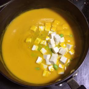 南瓜糊倒入锅里，小火加热。如果南瓜糊太稠请适量加点水，反之请大火加热，收干水份至你想要的浓稠度。
南瓜糊煮开后放入豆腐和毛豆