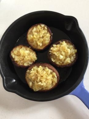 烤好的蘑菇，戴上手套取出来，以免烫手。把炒好的蒜蓉趁热放在蘑菇上。