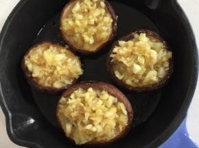 烤好的蘑菇，戴上手套取出来，以免烫手。把炒好的蒜蓉趁热放在蘑菇上。