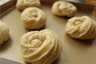 挽一个环，一头压在下面，一头从中间掏出来，两个头都要压住，避免发酵之后散开。全部都做好，放入烤盘。