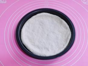 发酵好的面团取出排气，用擀面杖擀成大圆饼，放入披萨烤盘中。（披萨烤盘中刷上一层食用油）