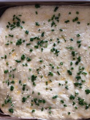 发酵好的面包表面刷蛋黄液，撒上葱花和白芝麻。