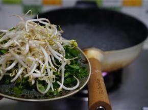 然后锅里加入清水煮开，水量多一点，这款轻奢不粘锅热的很快。水开之后将青菜及豆芽下锅煮至熟，再分别连汤盛在碗里，在碗里先加入少许的细盐及鸡精调一下味。