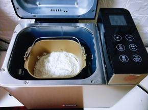 将面包桶放入面包机体中，启动面包机和面一个程序，和好的面团取出盖上保鲜膜进行发酵，发酵至原来的2.5倍大。