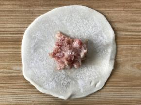 取一张饺子皮，中间放上适量肉馅；