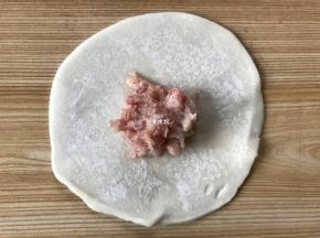 取一张饺子皮，中间放上适量肉馅；