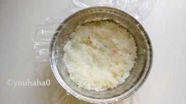 用一个碗或其他喜欢的容器，在容器里铺一层保鲜膜，在碗底铺一层放凉的糯米饭，用手压实。