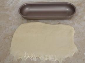 v将松弛好的面团用排气擀面杖擀成宽度和模具差不多长的长方形，下端用手指将面团拉扯开，方便粘合。