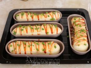 .发酵好的面包卷在表面放上芝士片，挤上沙拉酱和番茄酱，最后撒上葱花。