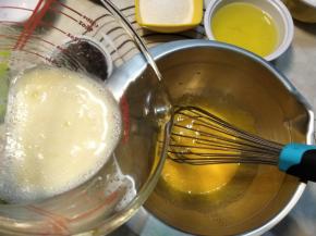 将玉米油与牛奶混合的液体缓慢的一点点的加入蛋黄糊中，并且用手动打蛋器搅拌均匀。