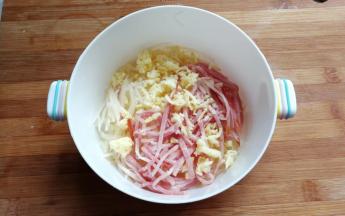 我们再把沥干的土豆丝和切好的培根丝，还有芝士碎一起放入大碗中。
