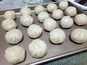 油酥和油皮均匀分成18分，一份油皮包裹一份油酥，像包包子一样，包好后如图。注意油皮要注意保湿，我一般用保鲜袋覆盖，保鲜膜太薄，一撩起来就容易皱巴巴，操作一个从袋子底下拿一个。全部包好后这样的继续覆盖保鲜袋，醒5-10分钟