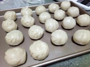 油酥和油皮均匀分成18分，一份油皮包裹一份油酥，像包包子一样，包好后如图。注意油皮要注意保湿，我一般用保鲜袋覆盖，保鲜膜太薄，一撩起来就容易皱巴巴，操作一个从袋子底下拿一个。全部包好后这样的继续覆盖保鲜袋，醒5-10分钟