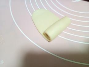 取一个剂子，收口朝上，按扁，用擀面杖从中间向上擀一下，向下擀一下，不要来回擀，容易混酥。擀好的长度大概比手稍微短一点点。然后右下至上卷起。