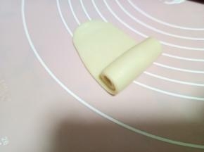 取一个剂子，收口朝上，按扁，用擀面杖从中间向上擀一下，向下擀一下，不要来回擀，容易混酥。擀好的长度大概比手稍微短一点点。然后右下至上卷起。