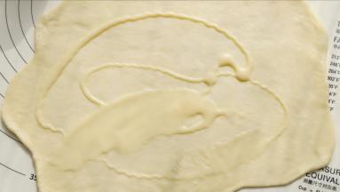 取一份面团擀开，抹一层炼奶。