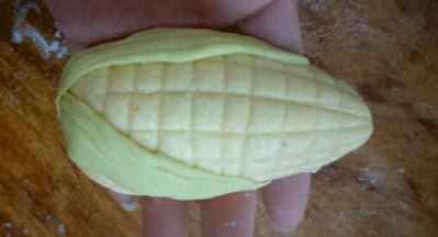 黄色面团揉圆，搓成一头尖，用刀切上横竖纹，贴上两片叶子做成玉米的形状