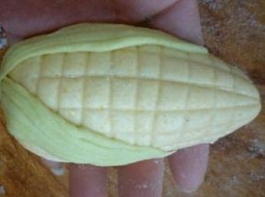 黄色面团揉圆，搓成一头尖，用刀切上横竖纹，贴上两片叶子做成玉米的形状