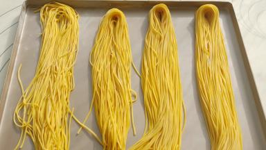 每切割到一定的长度机器按停，用剪刀剪断。撒上一层薄薄面粉防止粘连。都切割好后整齐的摆放在烤盘上。