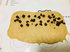 取一个面团，轻压按扁，擀长，翻面！翻面！翻面！将黑糖切成小块，放到面上，底部不放。每个面团黑糖块的量大概20到25克。