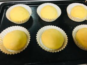 11、和制作菠萝包差不多，底部不需要包裹菠萝皮。包好后放入纸托中。刷上全蛋液，进行2次发酵。时间大概60分钟左右。发酵温度不要超过28度。温度高了菠萝皮就化了。