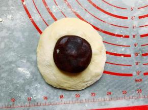 将松弛好的面团擀成圆形，翻面后包入豆沙馅，封好口，封口处朝下摆放。