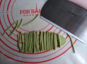 绿色面团擀成薄面片，用法焙客切面刀切出若干条细小的面条