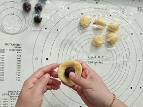 取一个面团按扁放入一个豆沙馅包好，收口捏紧。