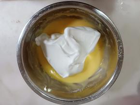 舀一勺蛋白霜加入蛋黄糊，画J字翻拌均匀。