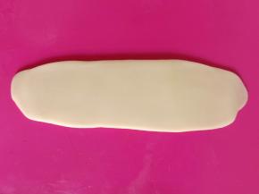 第二次擀卷，将面团按扁，擀成长条形。