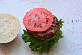 取一片面包，放上生菜、西红柿、肉饼，挤上沙拉酱，盖上另外一片面包，牛肉汉堡就做好啦