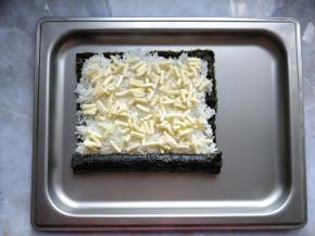 把一端的香肠卷起来，接口在米饭上压实。在米饭上撒少许马苏里拉奶酪碎。