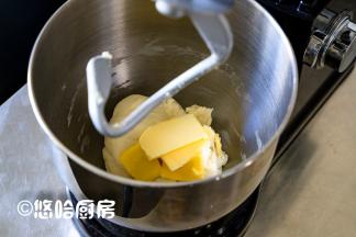 开启厨师机，先用低速揉成团，再用中速搅拌5分钟，放入室温下软化的黄油，继续搅打面团。