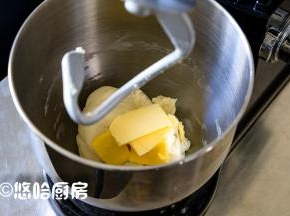开启厨师机，先用低速揉成团，再用中速搅拌5分钟，放入室温下软化的黄油，继续搅打面团。