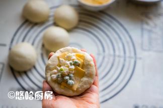 醒发后的面团用手拍扁，翻面后先放入半片左右撕开的芝士片，再放入适量的馅料。