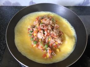 蛋液未凝固时放入米饭，叠起即可