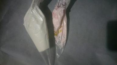 取适量蛋白拌入少许粉色食用色粉，分别装入裱花袋中，剪小口