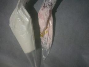 取适量蛋白拌入少许粉色食用色粉，分别装入裱花袋中，剪小口