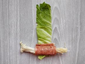 用培根将金针菇卷2-3圈，再放到包菜叶上，按照刚才卷的方向继续卷在外层。如果包菜叶比较厚脆，难卷的话，可以在热水中稍烫软一些再卷。