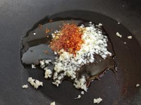 炒锅中倒入植物油，烧热后爆香蒜末和辣椒碎