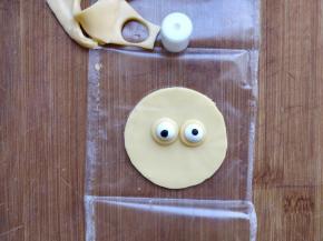 同样扣出两个眼睛的部分，把眼睛形的糖粒放在上面。也可以用黑白巧克力画出眼睛。