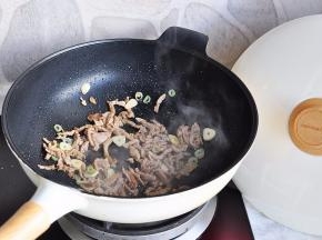 炒制肉丝变色后加入蒜片和葱花。