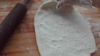 将发酵好的面团取出在案板上揉一下，将发酵时所产生的气体揉出去，然后用擀面杖将其擀成大片，在面片上面均匀的撒上一部分戗面所用的干面粉（戗面所用的干粉共计90克，大约分七至八次将其用完）