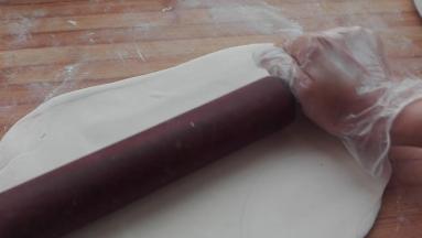 用擀面杖同样将撒着干粉，进行两次三折的面团擀成一个大的长方形