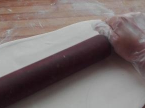 用擀面杖同样将撒着干粉，进行两次三折的面团擀成一个大的长方形