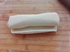 将擀好的面片其从一端卷起来，盖好保鲜膜，醒发20分钟